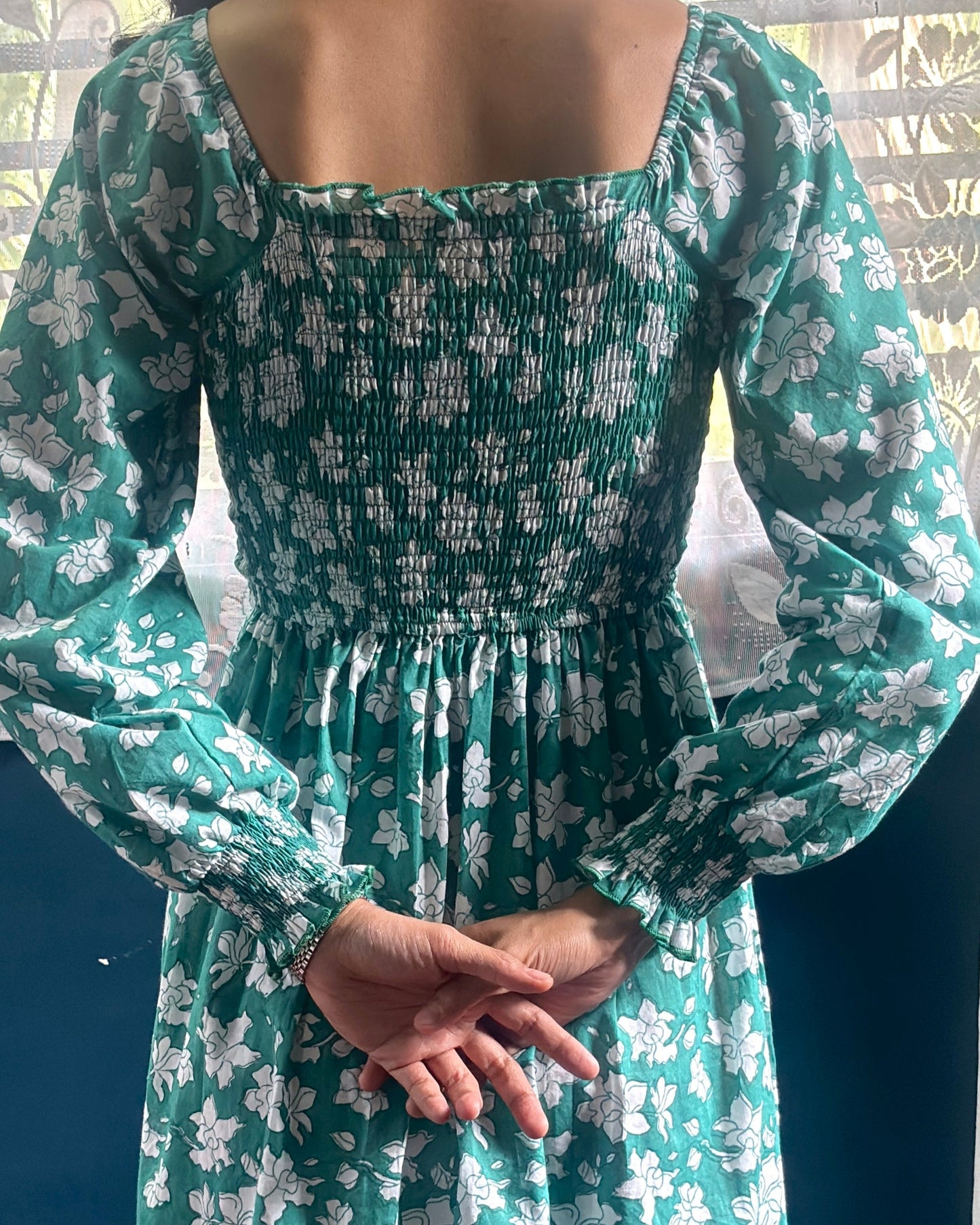 Person wearing a cute summer dress with smocked sleeves and ruffles.