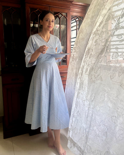 Woman in a blue and white striped dress that is vintage inspired and has retro charm. Shop this dress for garden parties and hosting brunches.